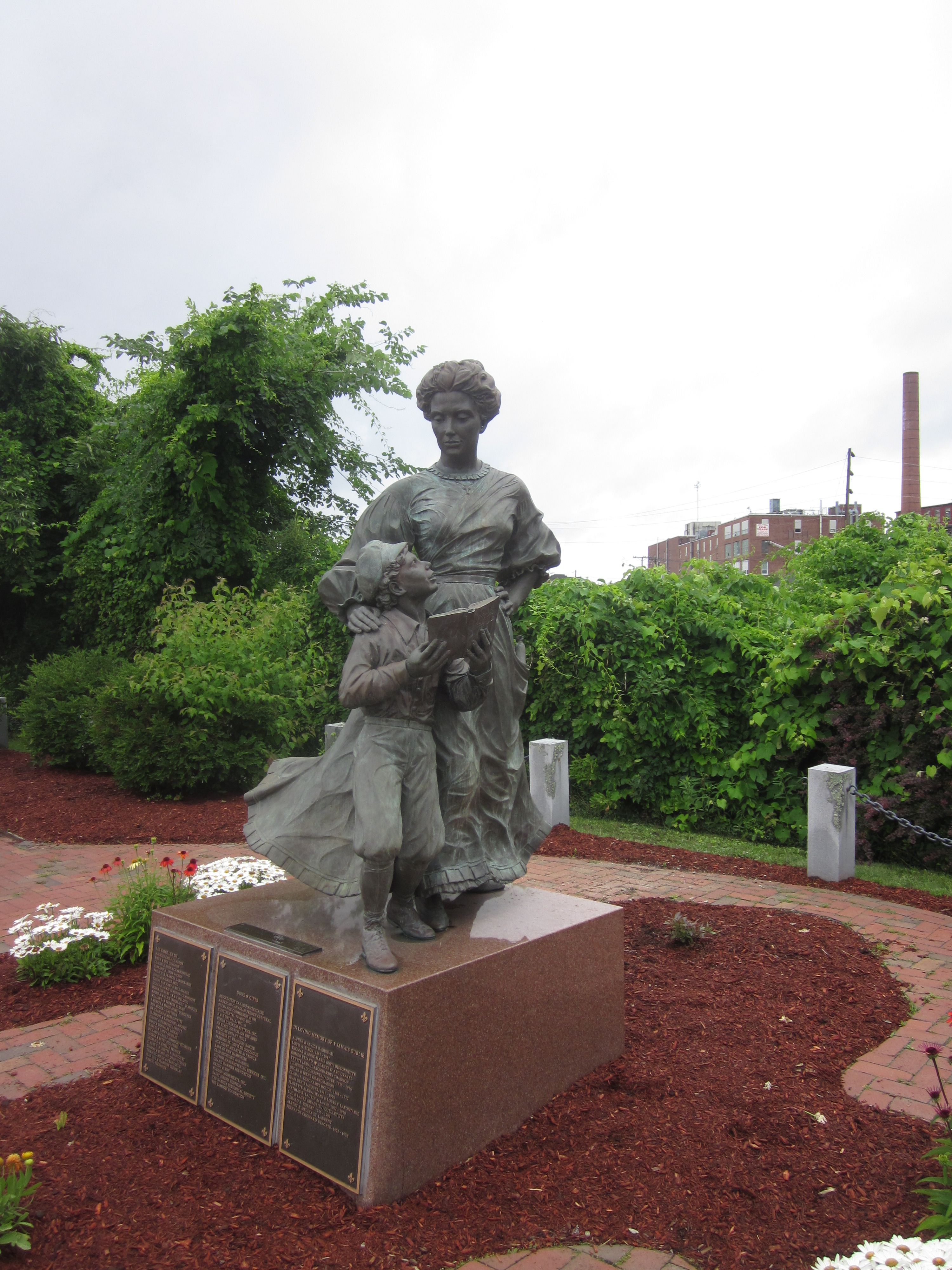 Statue of a woman and her young son holding a book.